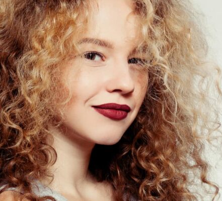 Ragazza sorridente con capelli biondi ricci crespi